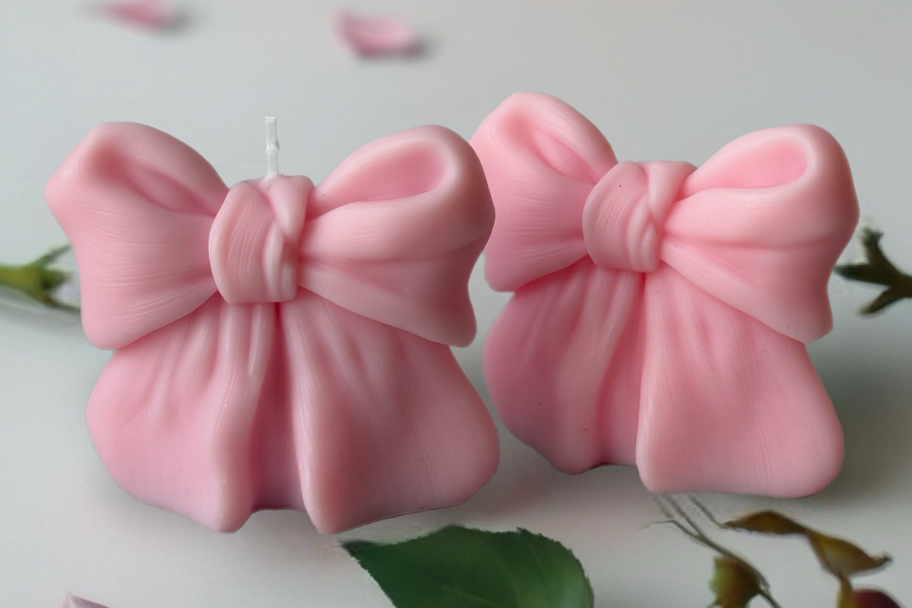 Pink bow-shaped objects on a surface with pink flowers in the background